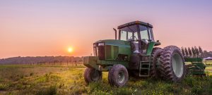 Tractor in a field on a farm at sunset